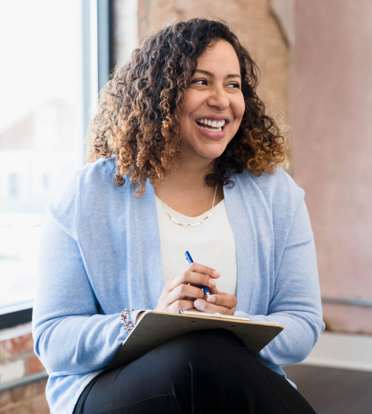 Woman chatting in group meeting holding notebook